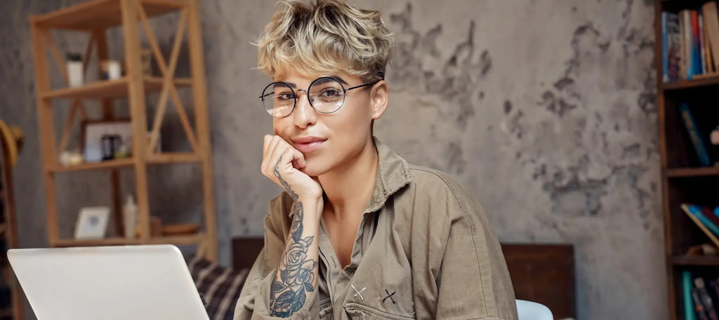 Profissional jovem com visual moderno e tatuagem trabalha em notebook em ambiente descontraído — capa do conteúdo sobre contratar profissionais sem experiência