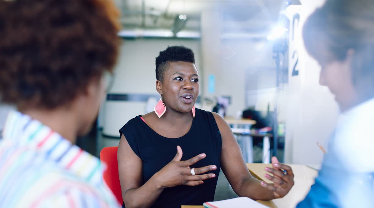 Mulher preta conversando com seus colegas de trabalho em uma reunião