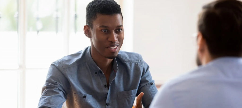 Homem jovem conversando com outras pessoas, capa do conteúdo sobre candidate experience