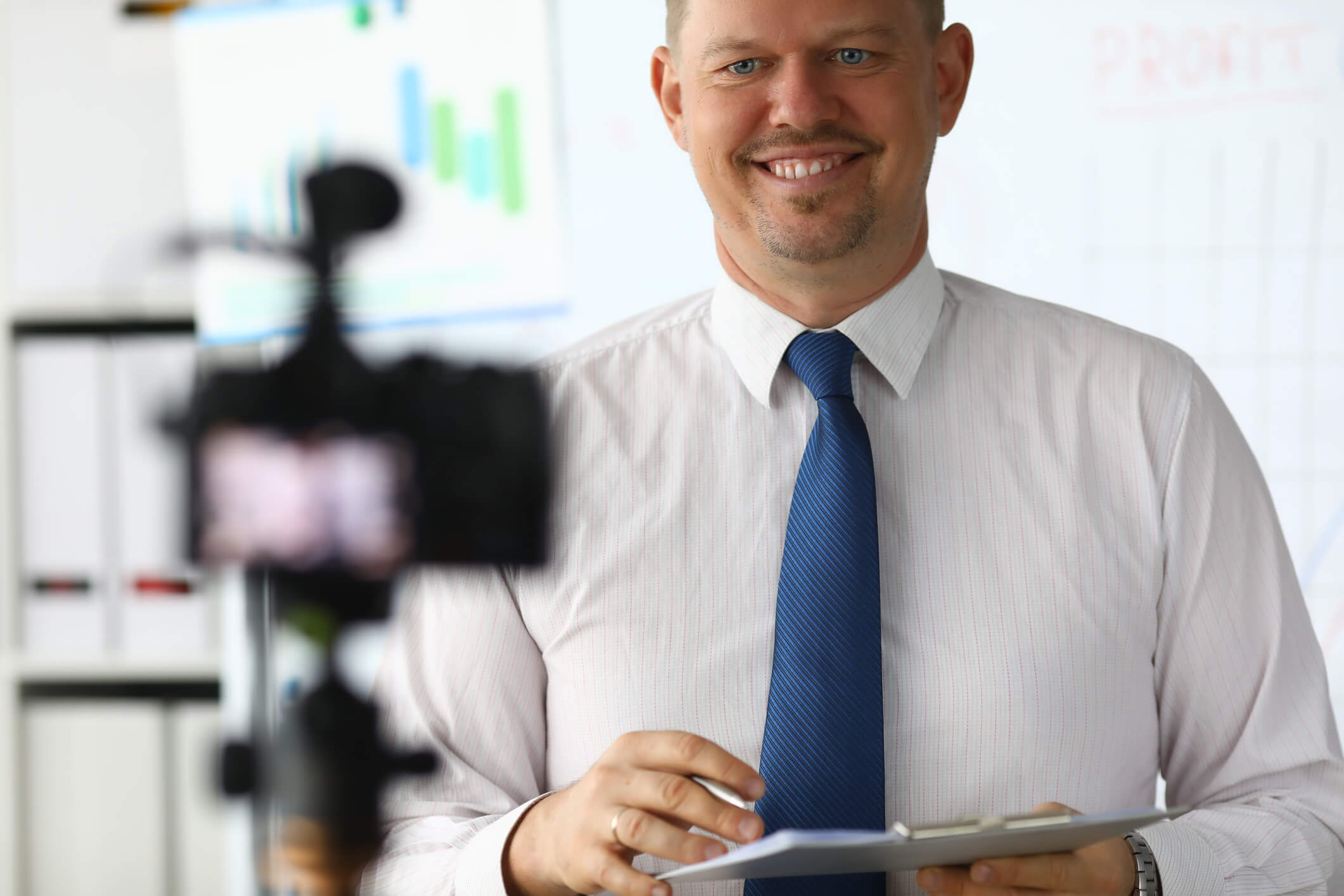 homem sorrindo de frente para uma câmera enquanto grava um vídeo currículo