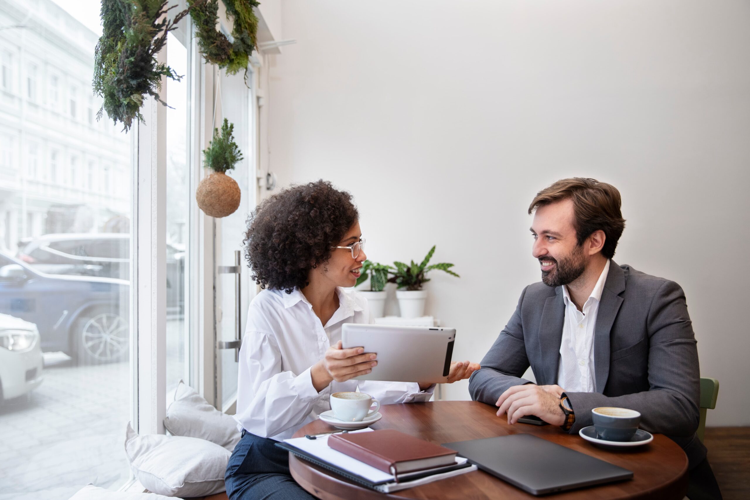 Dois colegas de trabalho conversando em um café. Ambos estão sorridentes.