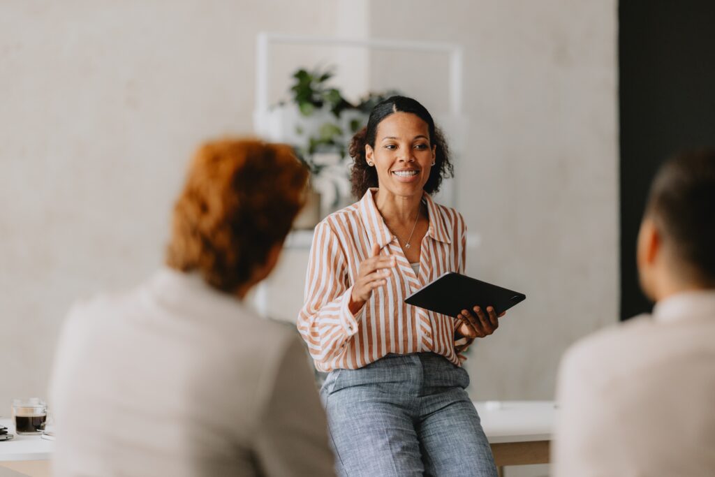 Dois homens e uma mulher em um ambiente de trabalho discutindo sobre ferramentas para gestão de pessoas.