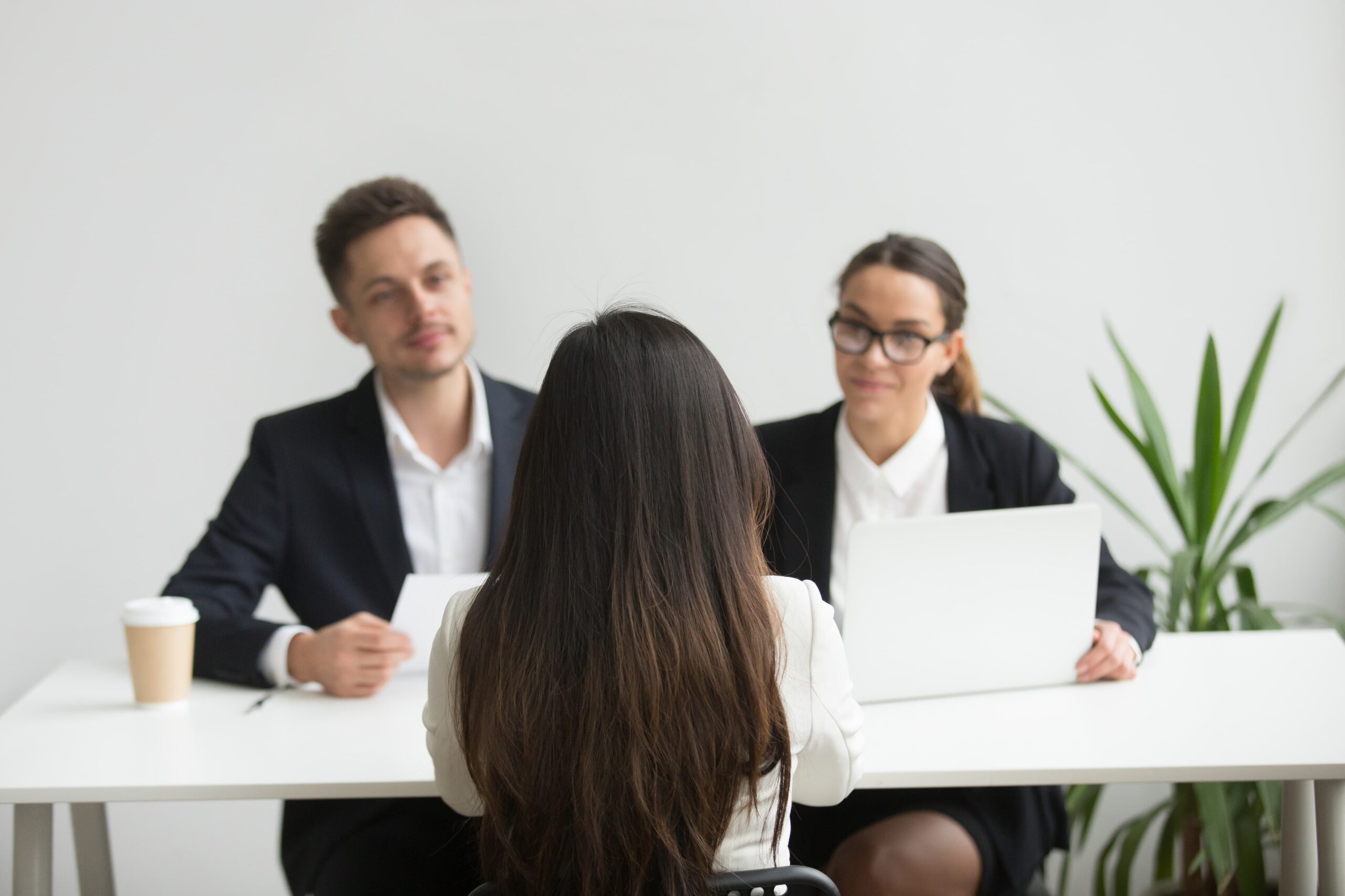 Mulher sendo entrevistada por duas pessoas em uma empresa.